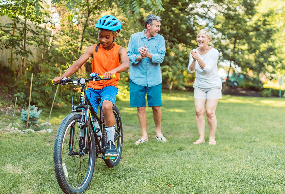 couple encouraging a boy riding a bike